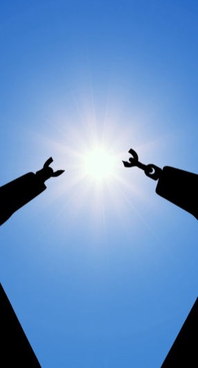 A hand breaking the chains that bind them