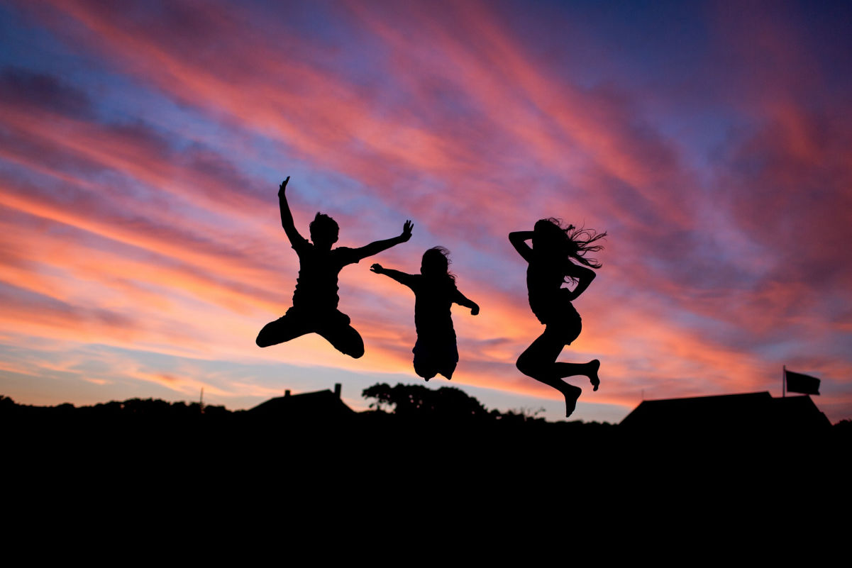Three people jumping in the air at dusk