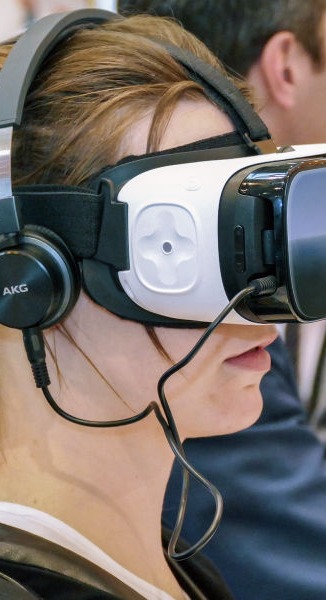 A woman wearing VR goggles and headset in a crowd of people