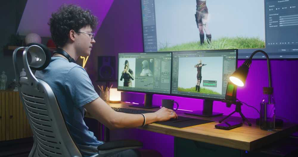 A focused individual working on 3D character modeling on dual monitors in a well-lit, modern workspace with ambient purple lighting.